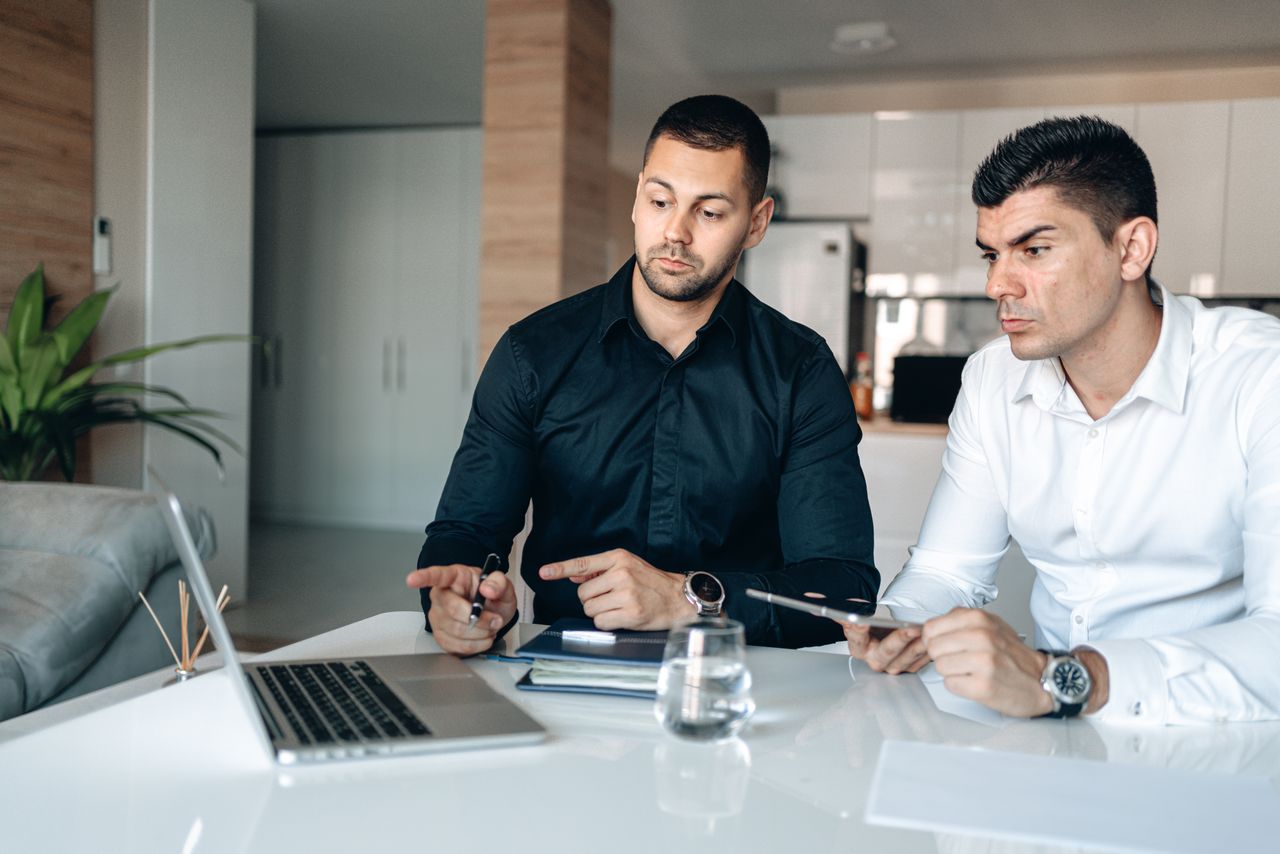 Two men in a modern office engaged in business collaboration using technology.